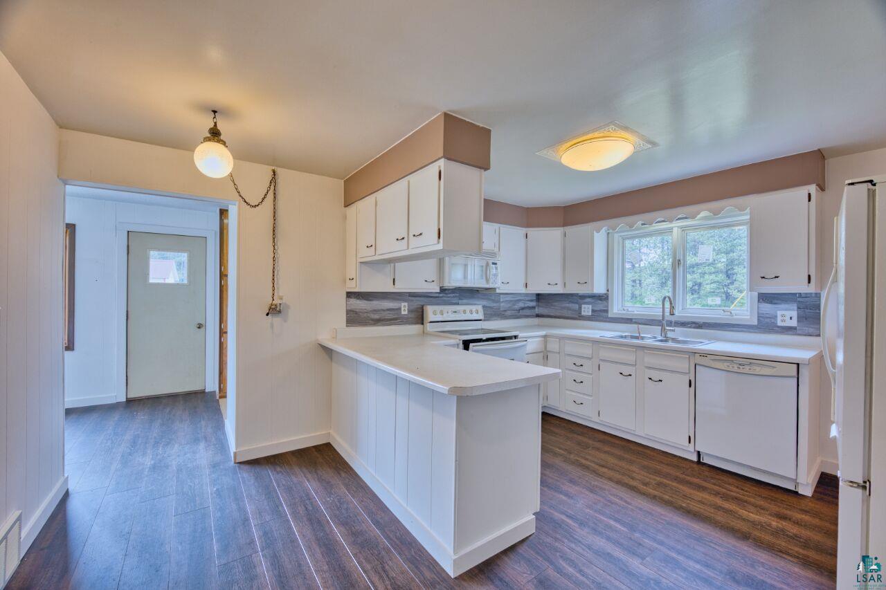 4755 Judd Road Gilbert, MN 55741 - Photo 9 of 50 Kitchen with white appliances, a sink, dark wood-style floors, a peninsula, and light countertops