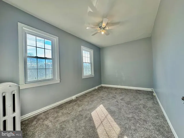 a view of an empty room with chandelier fan and fire place