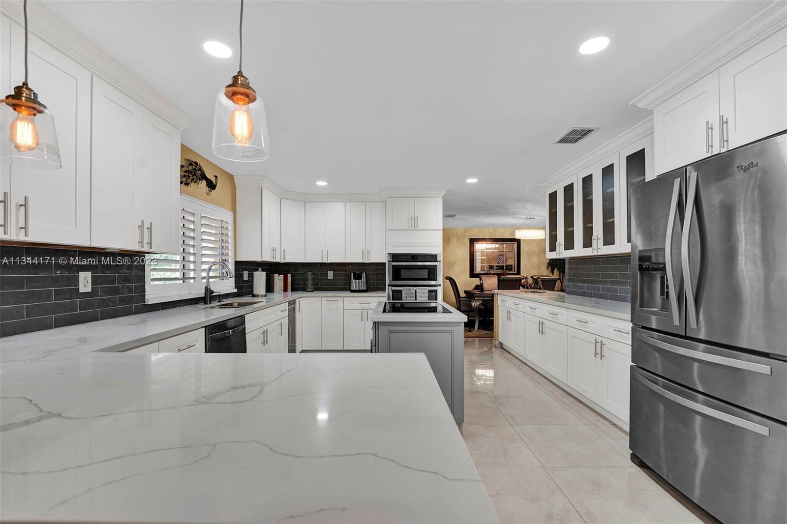 20100 Red Run Drive Hialeah, FL 33015 - Photo 11 of 61 a large white kitchen with stainless steel appliances kitchen island a stove a refrigerator a oven and a sink with cabinets