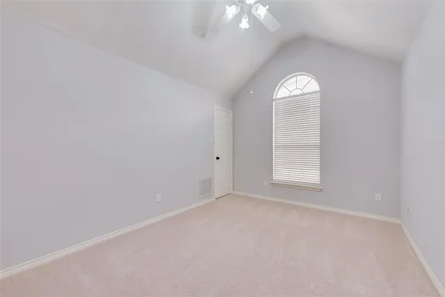 an empty room with windows mirror and fan
