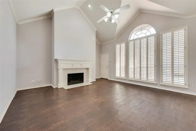 an empty room with windows fireplace and fans