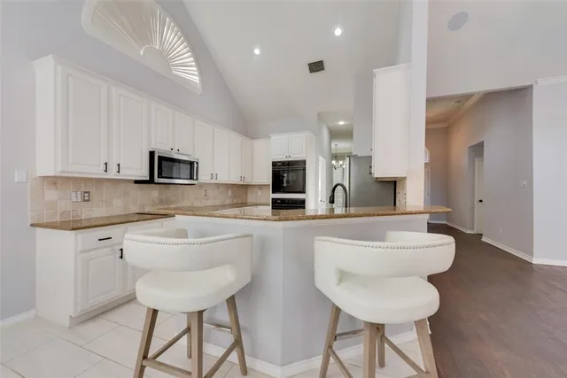 a kitchen with stainless steel appliances granite countertop a sink and a refrigerator