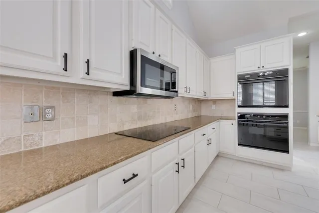 a kitchen with granite countertop white cabinets and stainless steel appliances