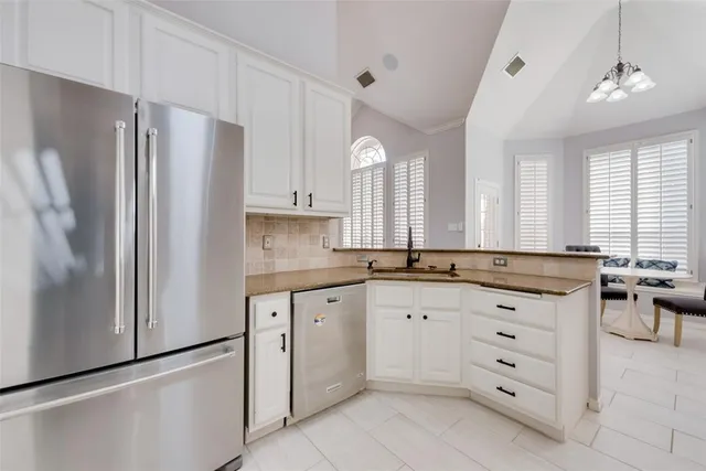 a kitchen with granite countertop cabinets a refrigerator a sink and dishwasher