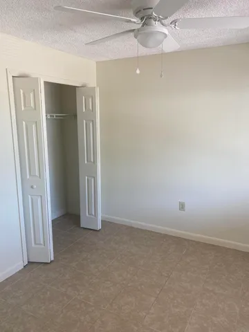 an empty room with a ceiling fan and closet area