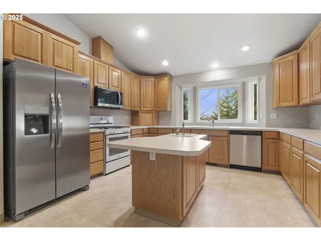 a kitchen with stainless steel appliances granite countertop a sink a stove a refrigerator a washer dryer and a refrigerator