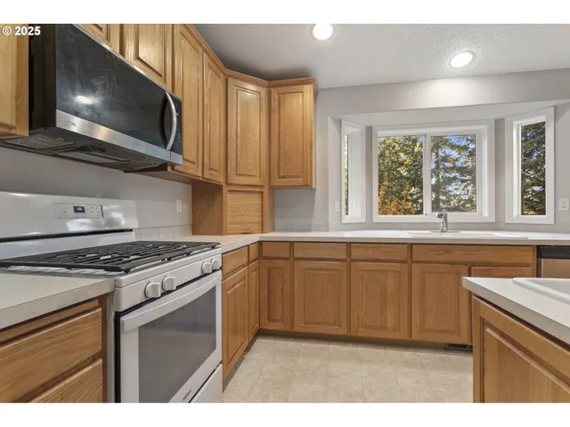 a kitchen with stainless steel appliances granite countertop a stove a sink and a microwave
