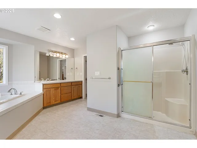 a bathroom with a tub a sink and a large mirror