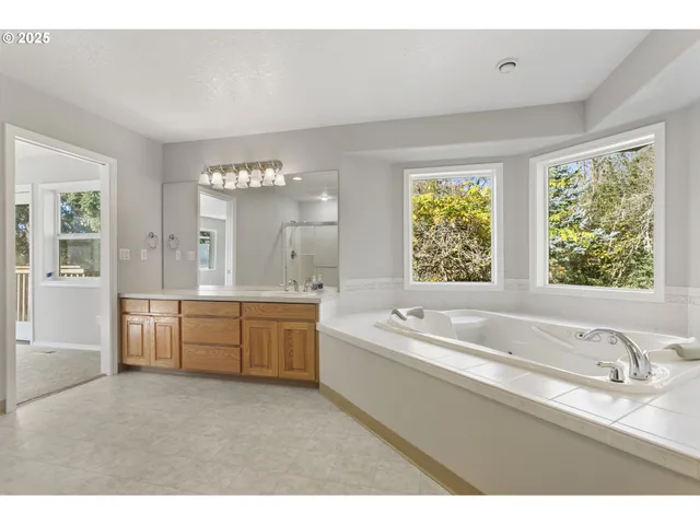 a bathroom with a granite countertop tub a sink and a window