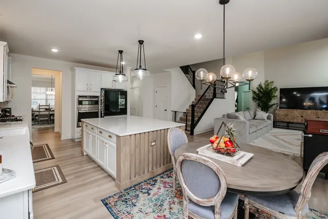 a kitchen with stainless steel appliances granite countertop a stove a kitchen island a dining table chairs and living room view