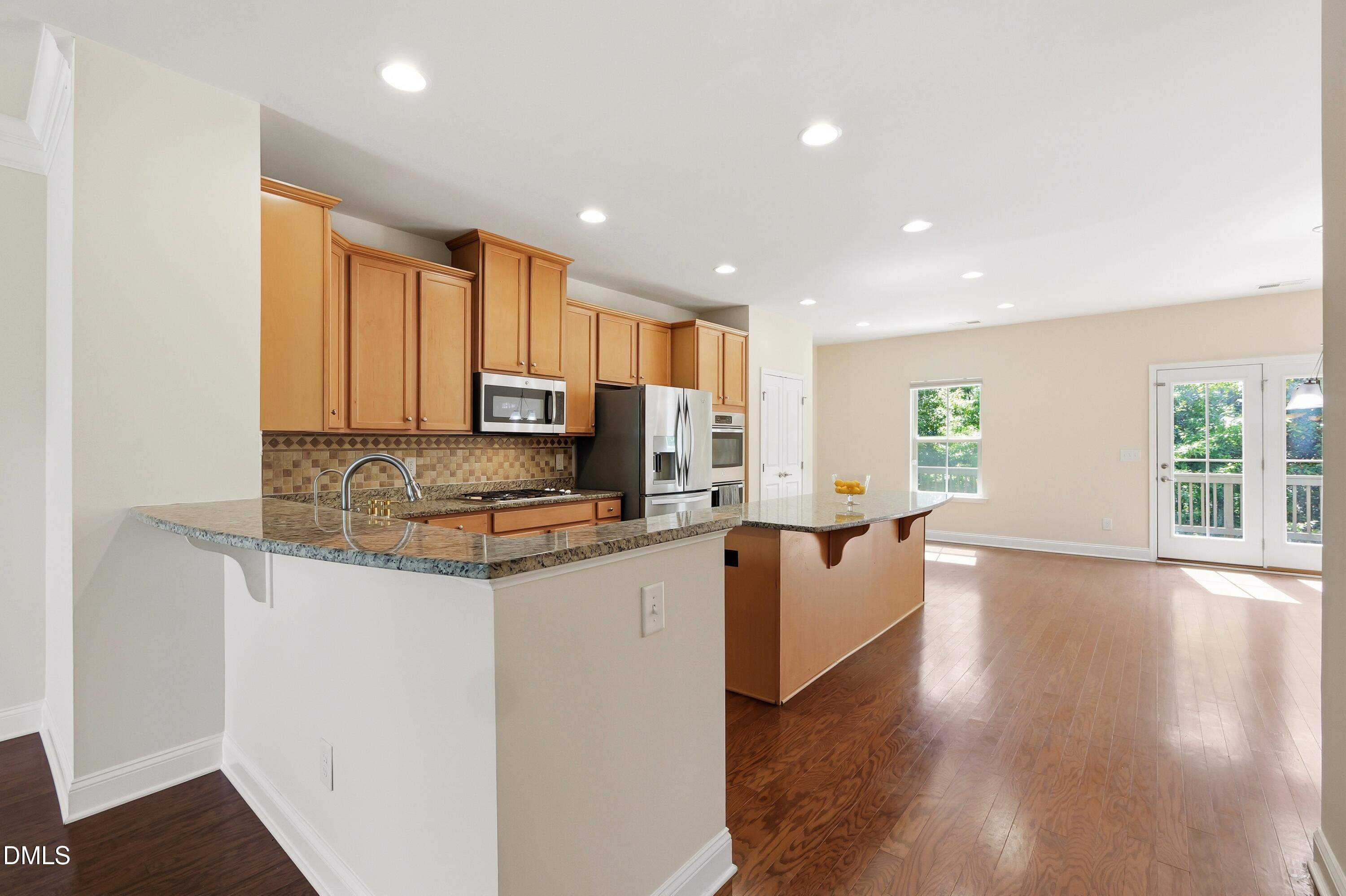 1004 Waymaker Court Apex, NC 27502 - Photo 6 of 30 a kitchen with granite countertop a stove top oven a sink a counter space and cabinets