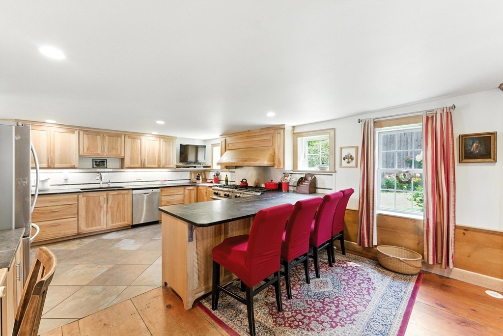 85 Dacey Road Conway, MA 01341 - Photo 16 of 42 a kitchen with a sink a kitchen island with chairs and wooden cabinets