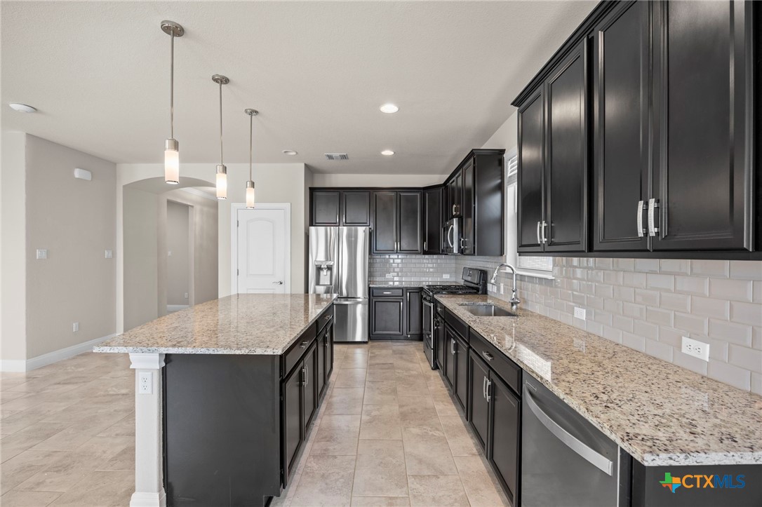 18215 Winnow Way Pflugerville, TX 78660 - Photo 11 of 21 a large kitchen with kitchen island granite countertop a sink a counter space and stainless steel appliances