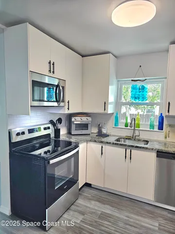 a kitchen with stainless steel appliances granite countertop a stove a sink and a microwave