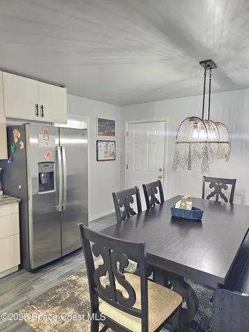 a kitchen with stainless steel appliances granite countertop a dining table chairs and refrigerator