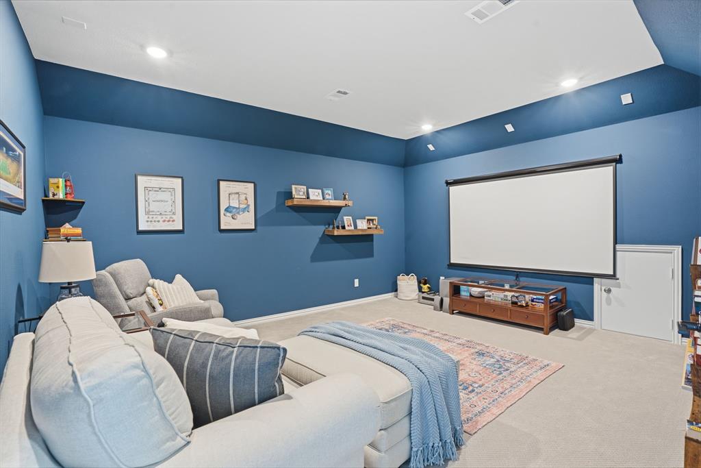 4202 Crown Run Road Midlothian, TX 76065 - Photo 21 of 34 Spacious entertainment room featuring a large projection screen, recessed lighting, wall-mounted floating shelves, and plush carpet flooring