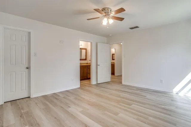 an empty room with a bathroom and a ceiling fan