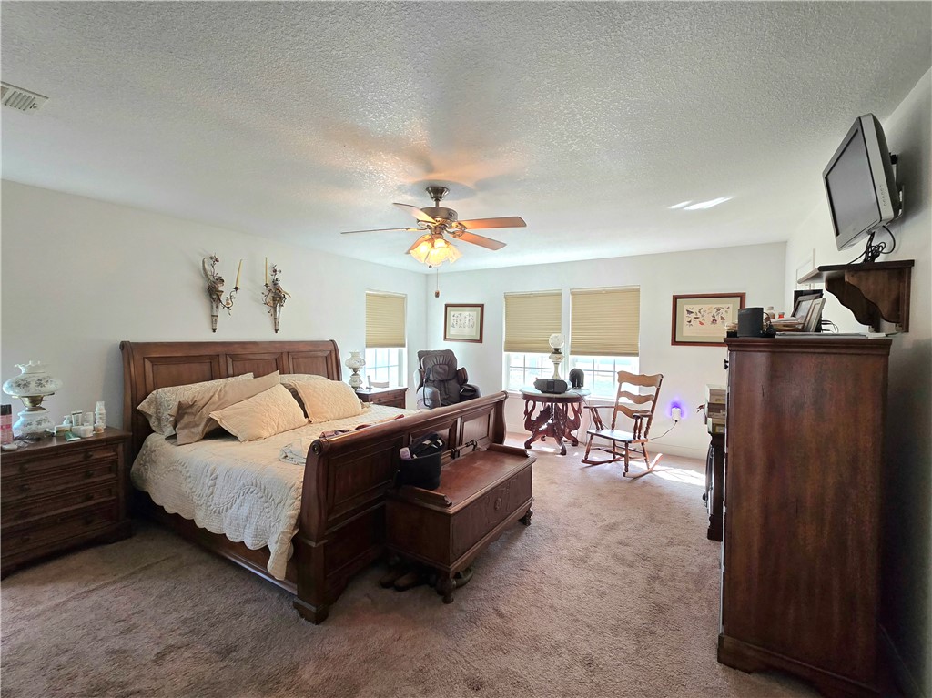 402 Shadow Arbor Circle Somerville, TX 77879 - Photo 13 of 26 a spacious bedroom with a bed a couch and a flat tv screen on a dresser