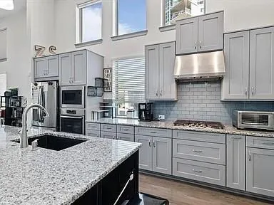 a kitchen with stainless steel appliances granite countertop a sink dishwasher stove and refrigerator with wooden floor
