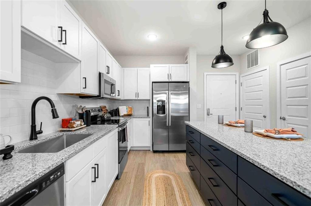 a kitchen with stainless steel appliances granite countertop a sink a stove and refrigerator
