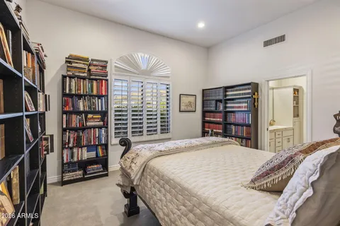 a bedroom with a bed a book shelf and a window