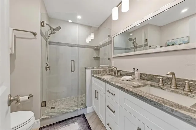 a bathroom with a granite countertop sink a toilet and shower