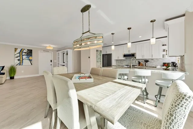 a kitchen with stainless steel appliances kitchen island granite countertop a table chairs and a refrigerator