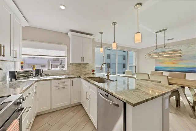 a kitchen with granite countertop stainless steel appliances a sink a counter top space and cabinets