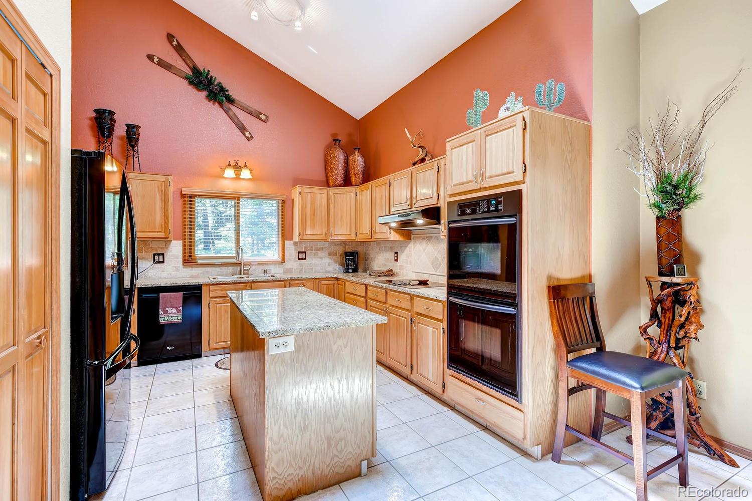 8045 Native Dancer Trail Evergreen, CO 80439 - Photo 8 of 29 a kitchen with stainless steel appliances granite countertop a refrigerator a stove and a sink with wooden floor