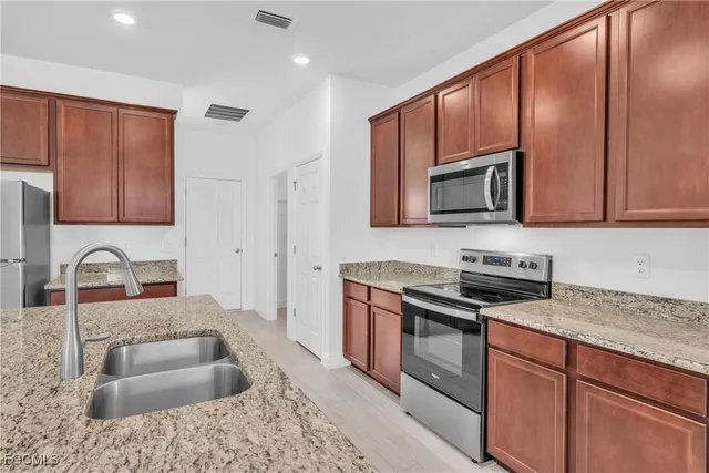 a kitchen with granite countertop a sink stove and refrigerator