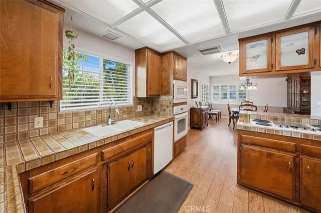 a kitchen with stainless steel appliances granite countertop wooden cabinets a sink dishwasher a stove and a refrigerator with wooden cabinets