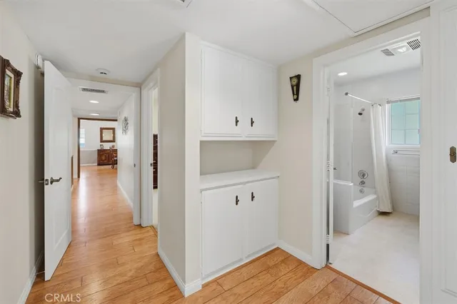 a view of a hallway with wooden floor and a bathroom