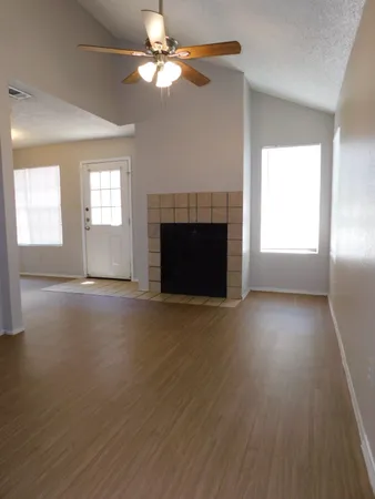 an empty room with windows fireplace and a kitchen view