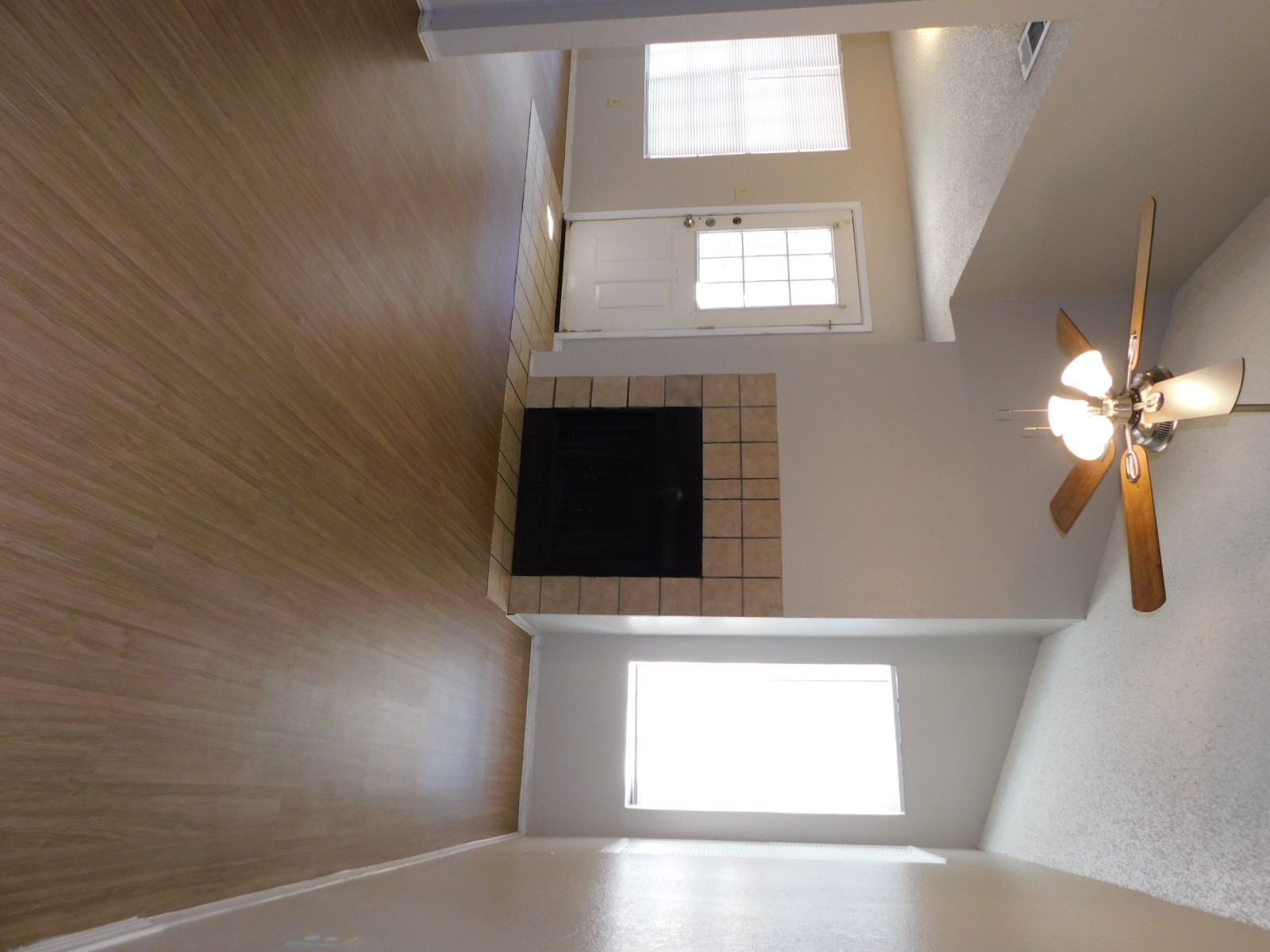 an empty room with windows fireplace and a kitchen view