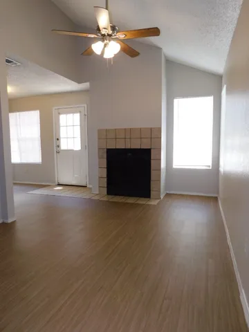 an empty room with windows fireplace and a kitchen view