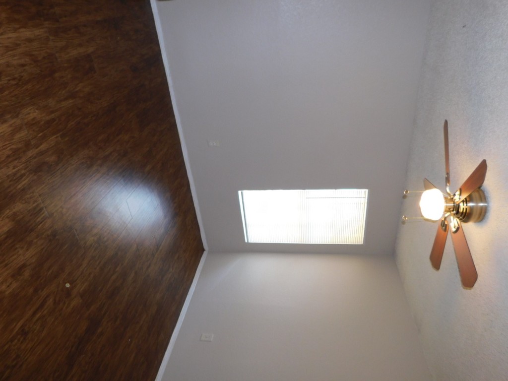 2223 Katy Lane, Unit B Georgetown, TX 78626 - Photo 9 of 11 an empty room with wooden floor fan and windows
