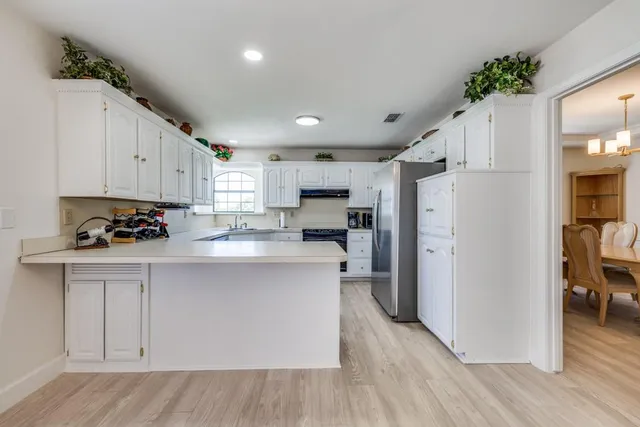 a kitchen with white cabinets and refrigerator