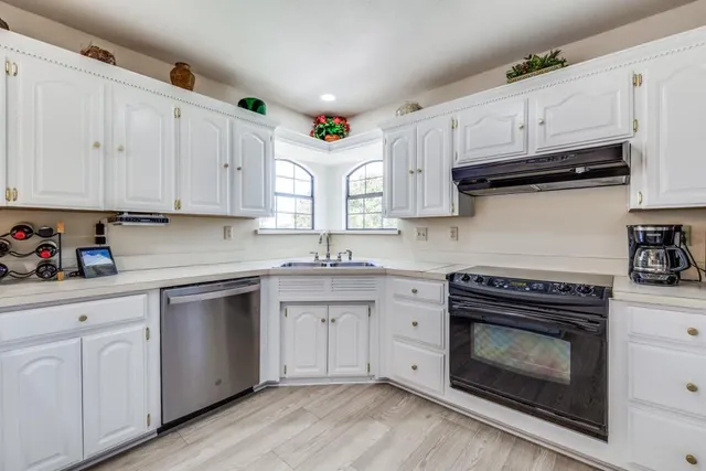 a kitchen with granite countertop white cabinets and white appliances