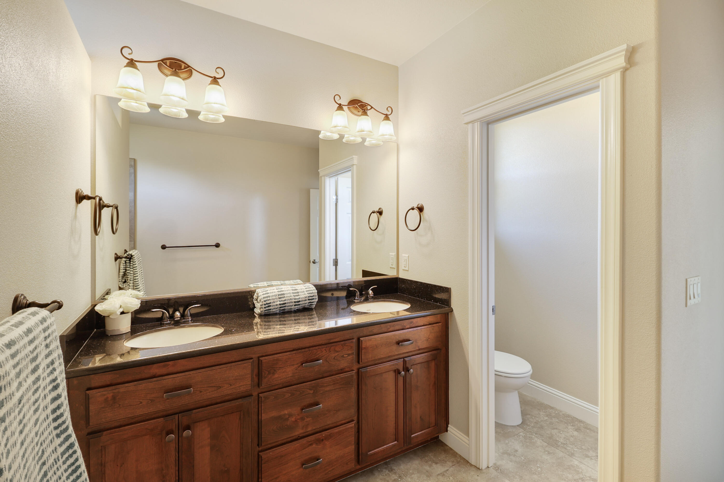 3863 Indian Wells Lane Redding, CA 96002 - Photo 32 of 63 a bathroom with a granite countertop sink a toilet and a mirror
