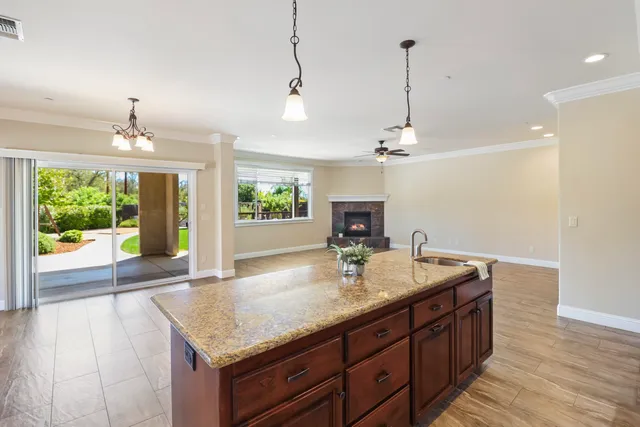 a kitchen with kitchen island granite countertop a sink and a wooden floors