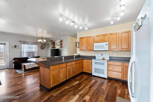 a large kitchen with kitchen island a stove a sink dishwasher a dining table and chairs with wooden floor