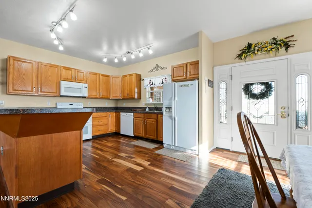 a kitchen with stainless steel appliances granite countertop a refrigerator a sink dishwasher and white cabinets with wooden floor