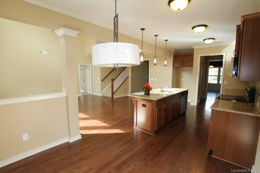 2186 Bluebell Way, Unit 170 Tega Cay, SC 29708 - Photo 6 of 15 a kitchen with stainless steel appliances kitchen island granite countertop a stove a refrigerator a sink a dining table and chairs with wooden floor