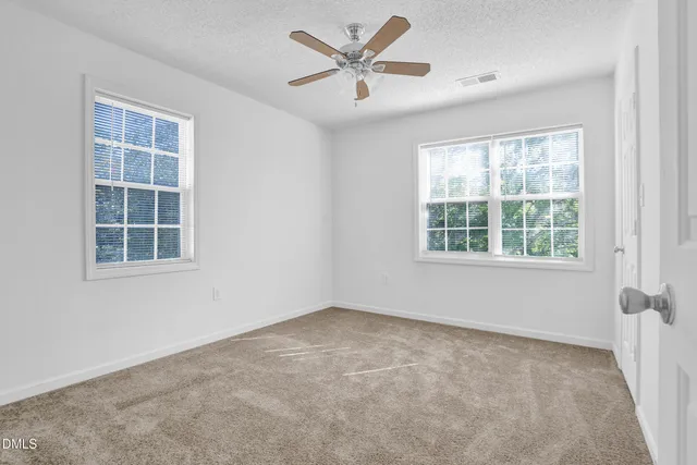 an empty room with a window and a fan