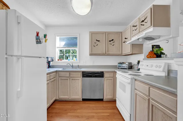 a kitchen with a sink a stove a refrigerator and white cabinets