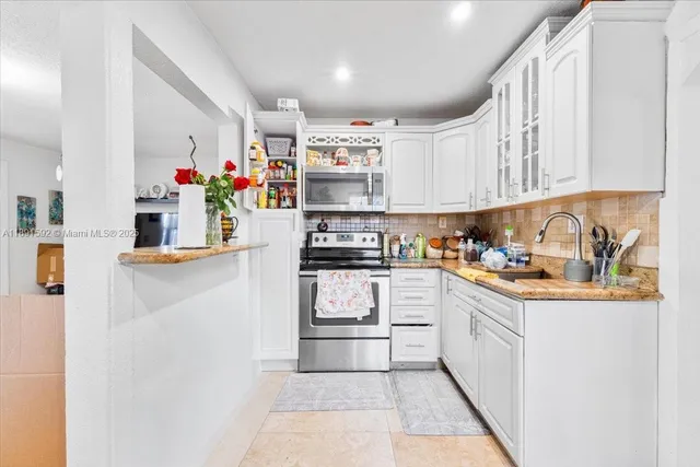 a kitchen with granite countertop lots of clutter and stainless steel appliances