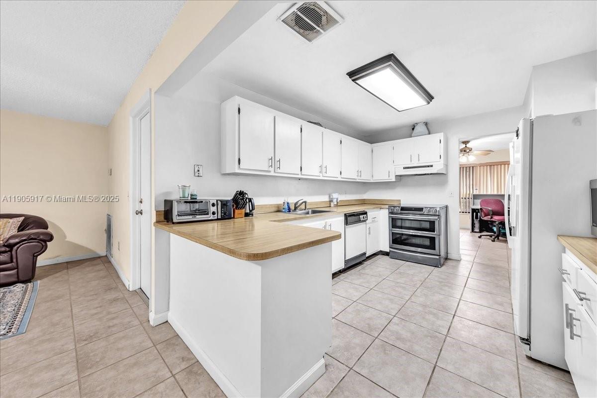 3930 Northwest 79th Way Davie, FL 33024 - Photo 11 of 33 a kitchen with granite countertop a sink a counter top space appliances and cabinets