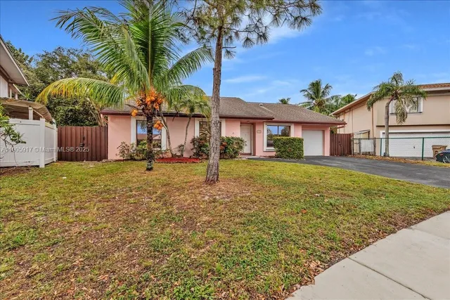 a front view of a house with a garden and palm trees