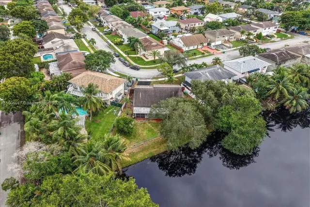 an aerial view of a residential houses with outdoor space and trees all around