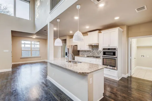 a kitchen with stainless steel appliances granite countertop a sink a stove and a wooden floors